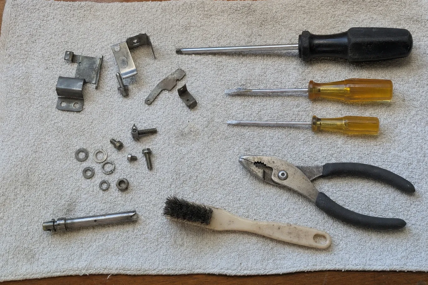 Ventilation hardware laid out on a cloth — mounting brackets, clips, a length of tube, fasteners, a wire brush and hand tools